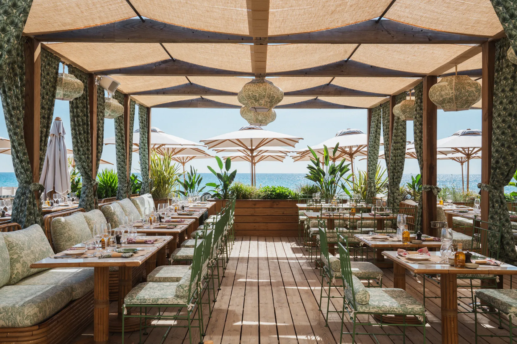 Table dressée pour un déjeuner en plein air au restaurant de plage Cybele avec vue sur la Méditerranée.